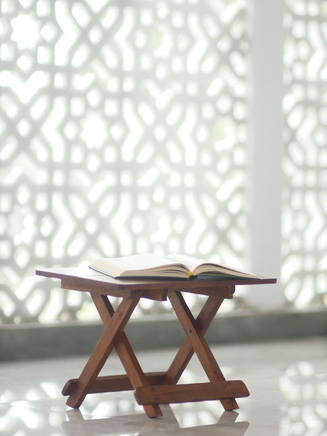An open book rests on a small wooden table.