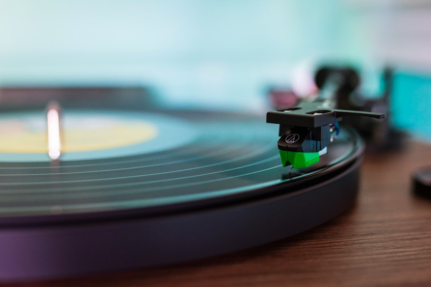 Green stylus resting on a spinning black vinyl record.
