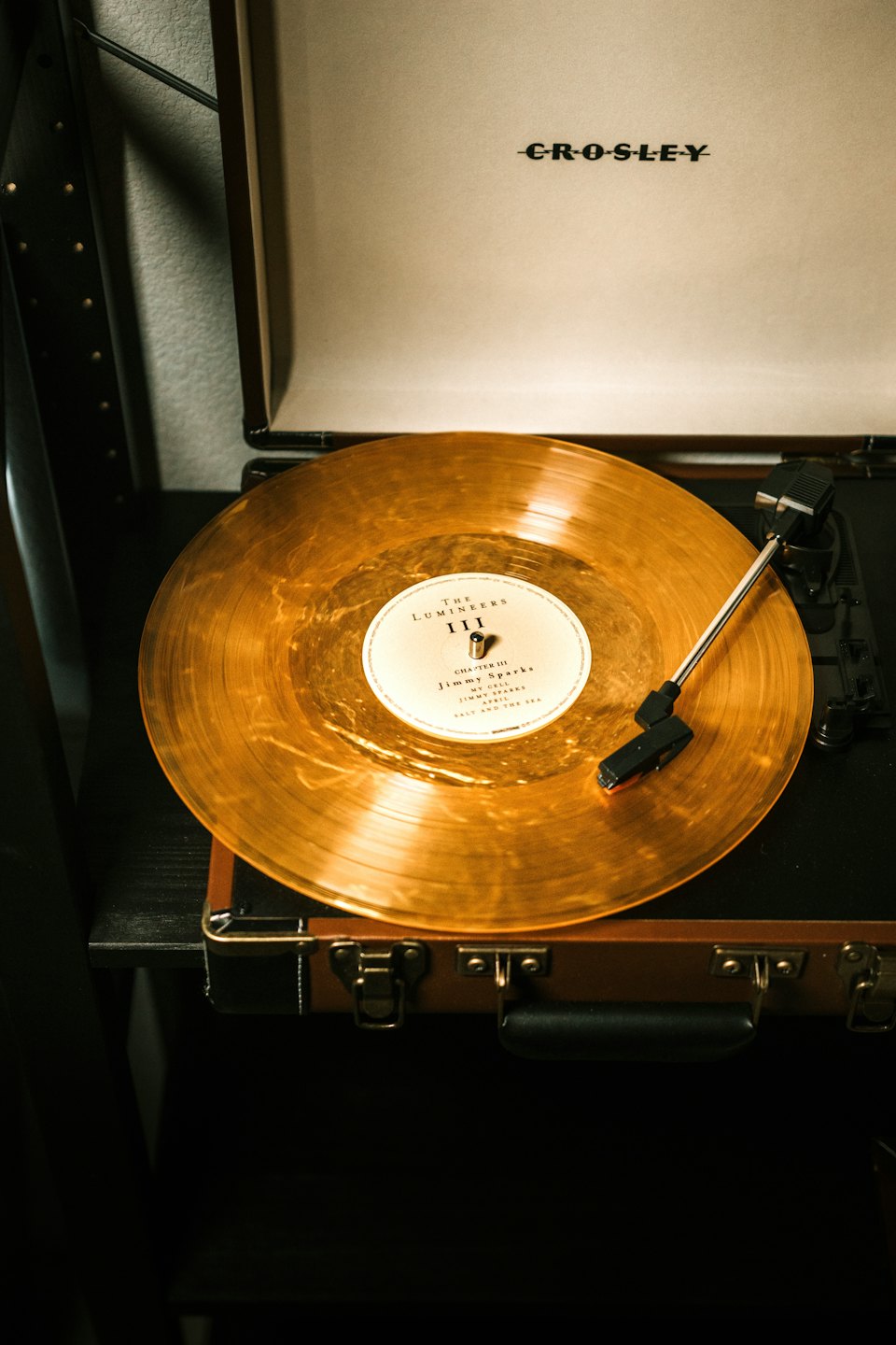 A golden vinyl record spins on a vintage portable turntable.